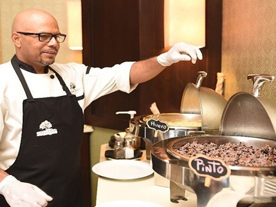 5-	Picture of food being prepared at the Costa Rica Medical Center Inn, San Jose, Costa Rica.  The picture shows a chef overlooking the food service.